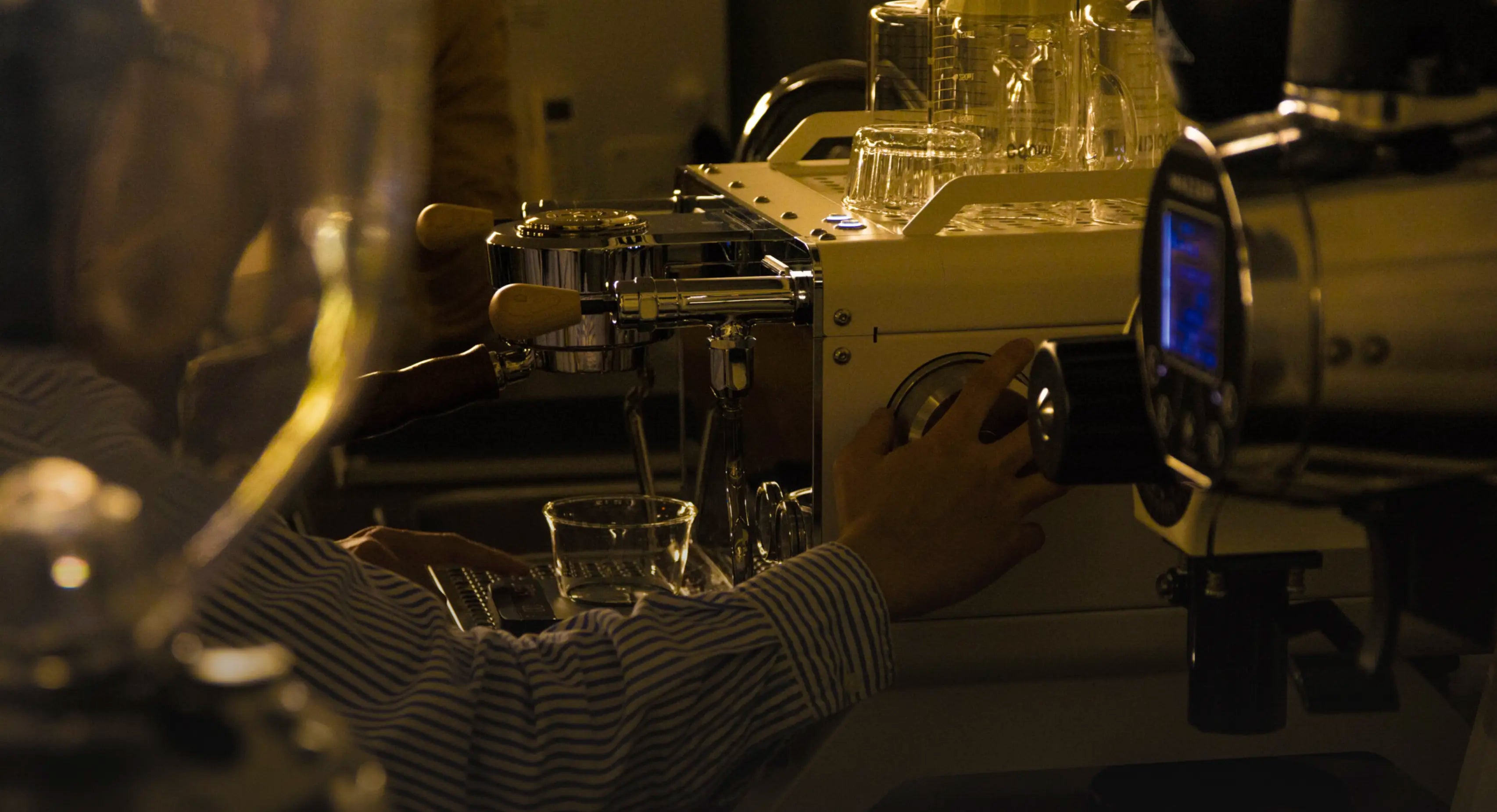Person operating an El Rocio Ragen Espresso machine with glassware in a laboratory setting